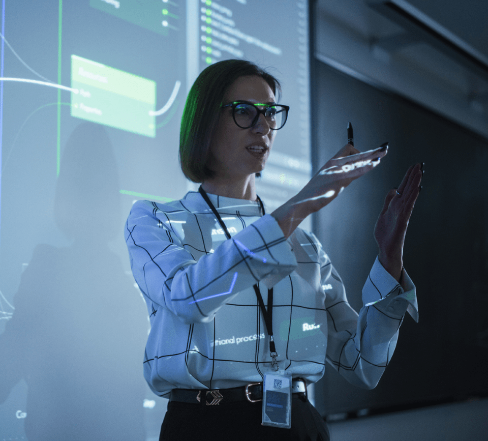 A female professional discusses business concepts in front of a larger audience, engaging the listeners with her presentation. A female professional discusses business concepts in front of a larger audience, engaging the listeners with her presentation.
